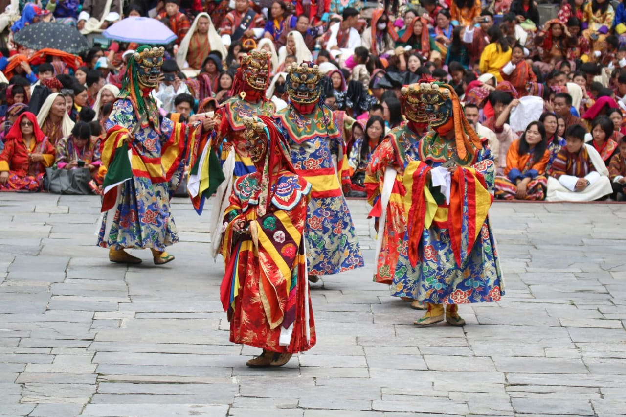 Bhutanese masked dancers performing a traditional Cham dance during a cultural festival.